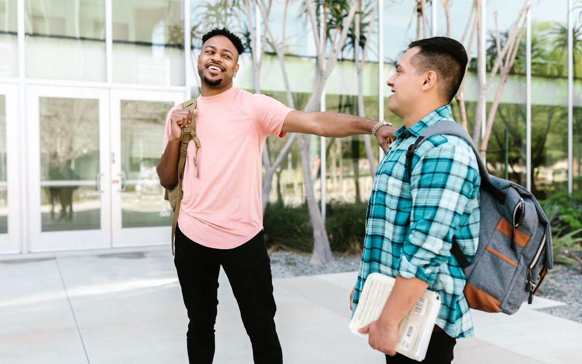Two smiling students talking outside a campus building