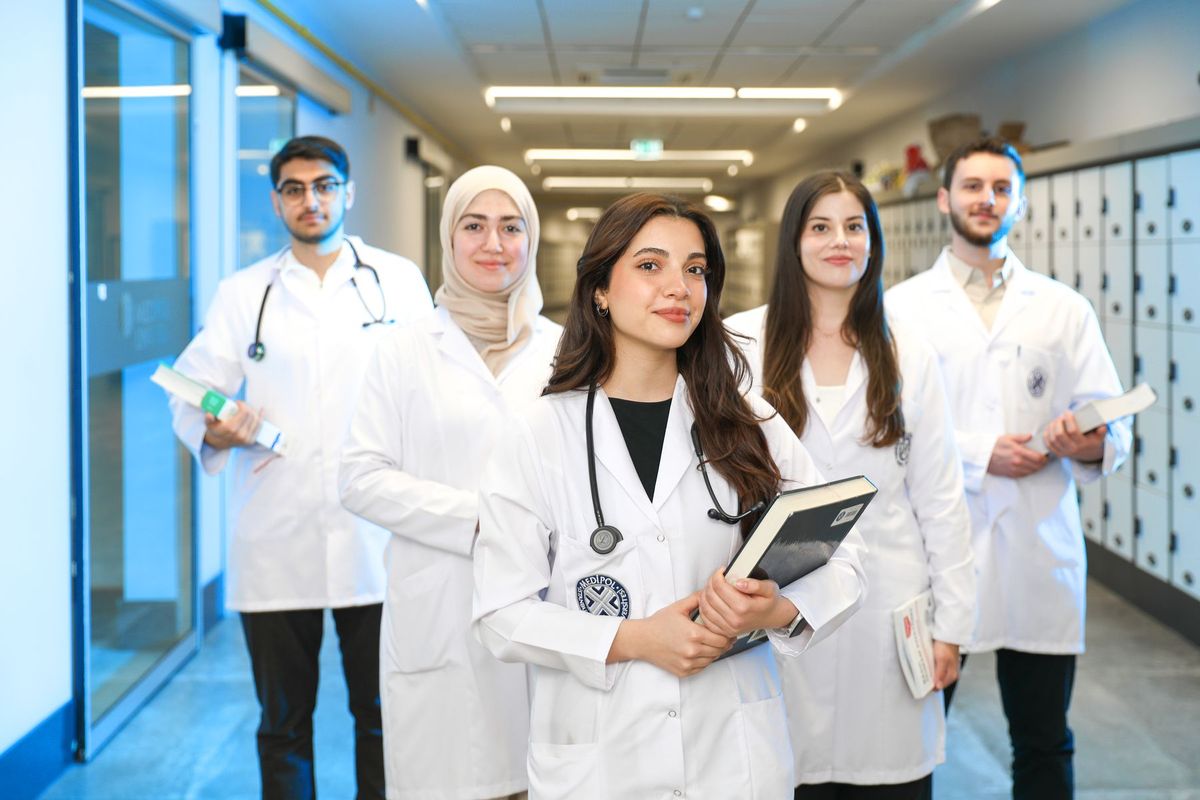 Medical students in white coats walking down a corridor