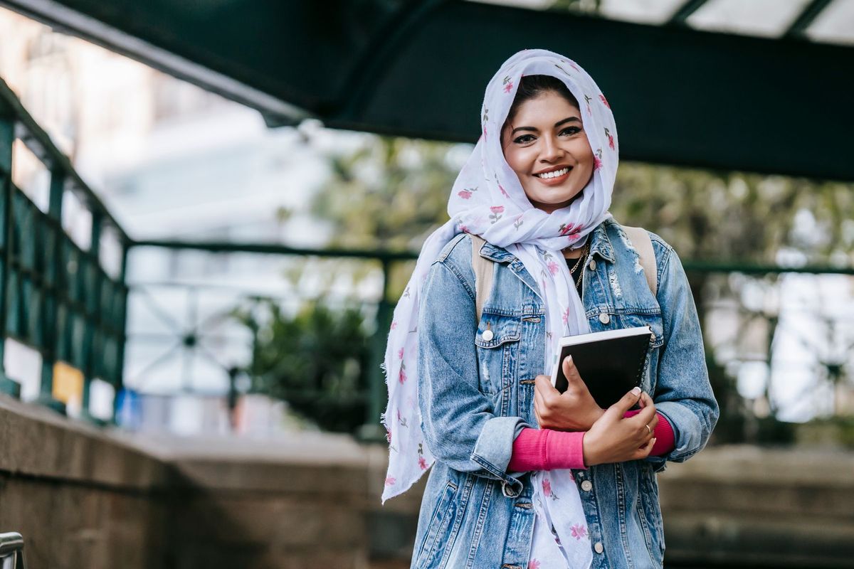 Smiling student holding a notebook outdoors