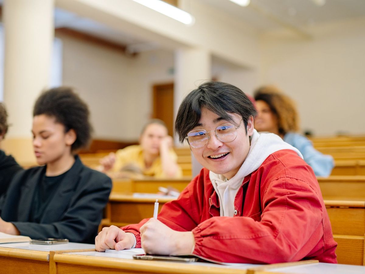 Smiling student writing notes in a lecture hall